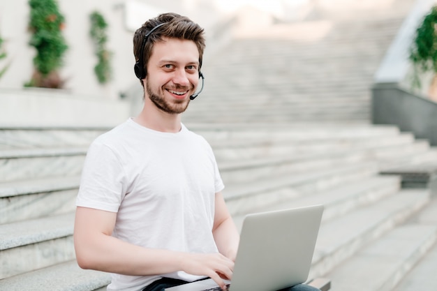 Man with headset and laptop outdoors