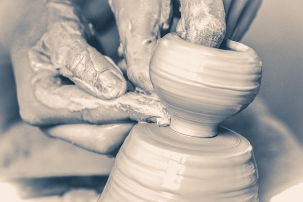 A man with his hands dub wall jug, which he sculpts out of clay on a circle. Create clay vessel. Modeling white-clay, shaping vessel. Caucasian man making vessel Cclay in circle.