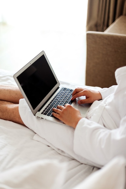 A man with a laptop on the bed the man in the bedroom is lying on a bed with a computer on his lap a...