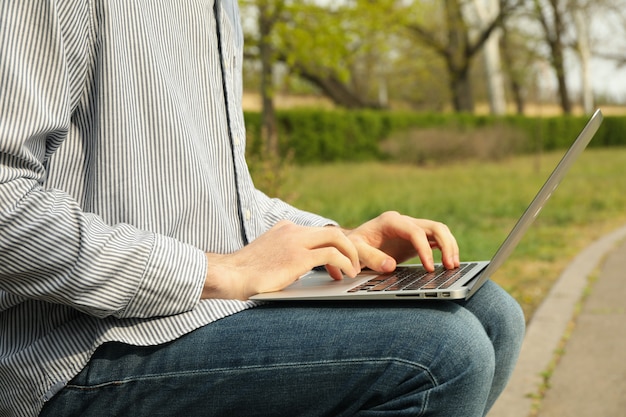 Man with laptop works in park. Outdoor work