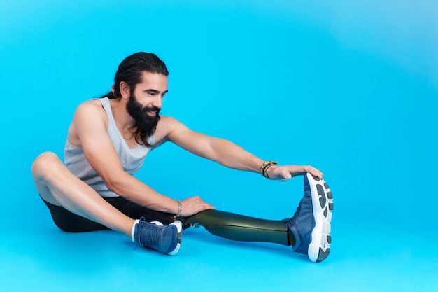 Man with a leg prosthesis sitting stretching the femoral muscle