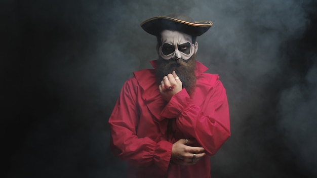 Photo man with long beard dressed up like a pirate for halloween over a black background with smoke coming out.