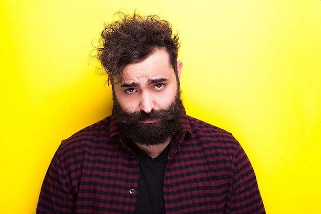 Man with a long beard looking at the camera on yellow background