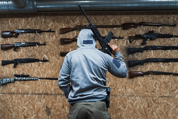 A man with an M4A1 rifle near the wall with a weapon in a shooting range Photo from the back