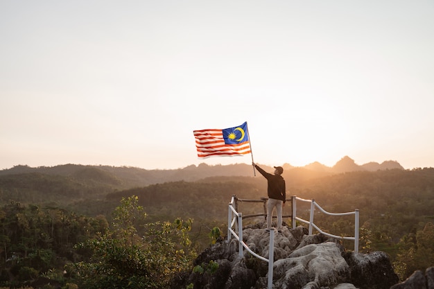 Man with malaysian flag of malaysia on top of the mountain