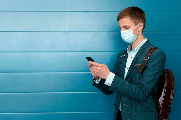 Man with medical mask and backpack using smartphone