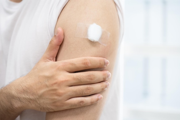 A man with medical plaster on arm after get covid 19 vaccine