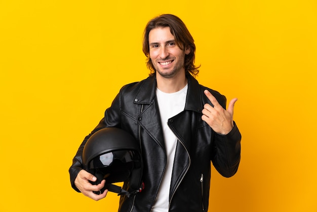 Man with a motorcycle helmet isolated on yellow giving a thumbs up gesture