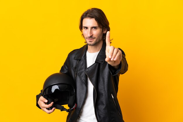 Man with a motorcycle helmet isolated on yellow showing and lifting a finger