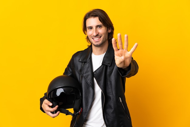 Man with a motorcycle helmet isolated on yellow wall happy and counting four with fingers