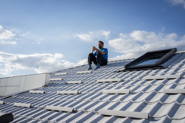 Man with phone on the top of house roof