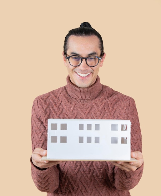 Man with ponytail and glasses holding a model of a house architect concept