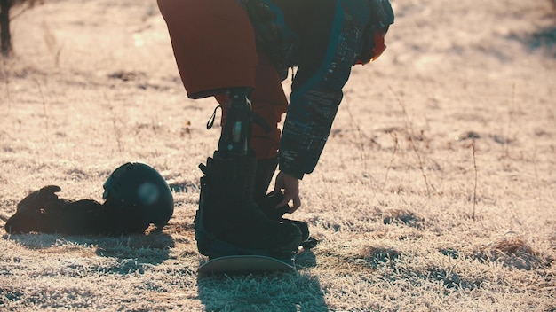 A man with prosthetic leg standing on the board and setting boots on it