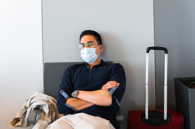 Man with protective face mask sleeps sitting on a chair in a waiting room in airport during pandemic