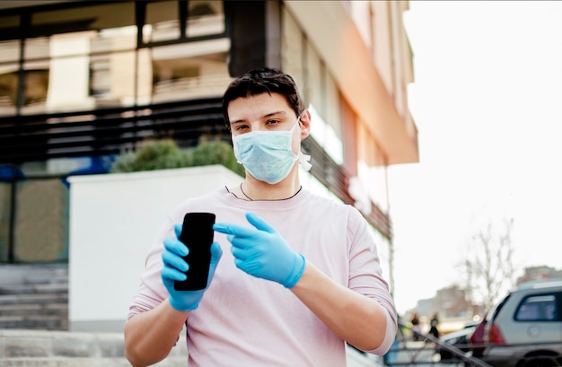 Man with protective medical wear using smartphone walking in the City Street.