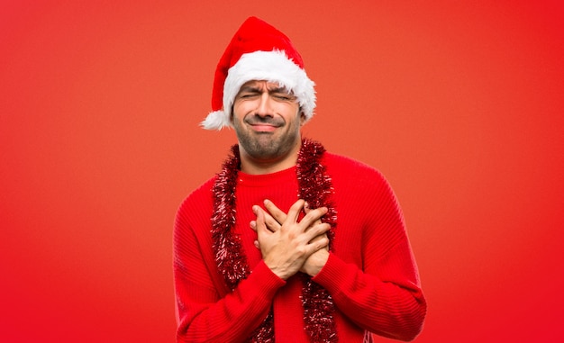 Man with red clothes celebrating the Christmas holidays having a pain in the heart 