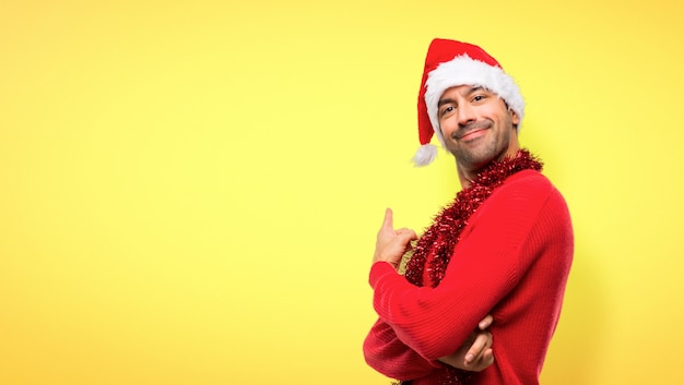 Man with red clothes celebrating the Christmas holidays pointing back with the index finge