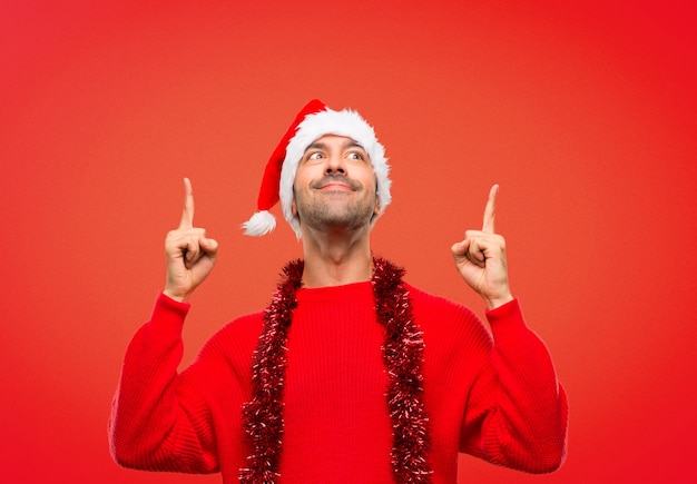 Man with red clothes celebrating the Christmas holidays pointing with the index finger