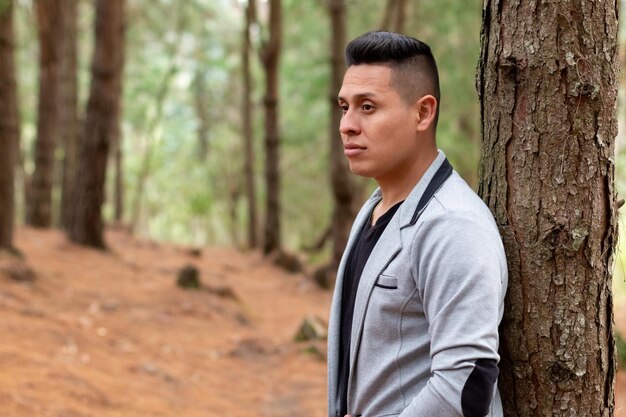 Man with sexy look wearing a gray blazer, in a forest of orange tones