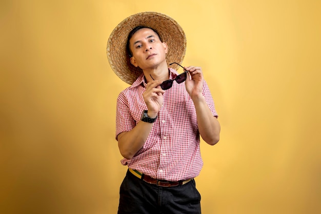 Man with a shirt and hat holding sunglasses standing