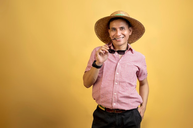 Man with a shirt and hat holding sunglasses standing