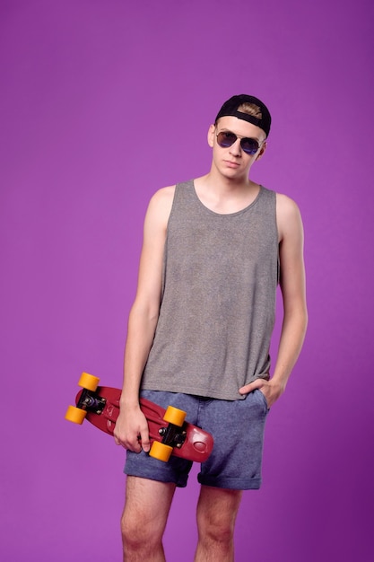 Man with skate board in hand on purple background, penny little board