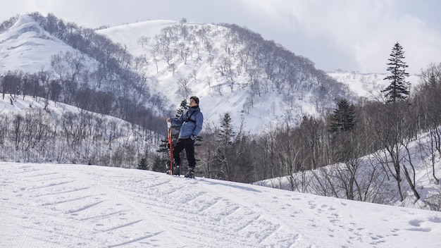 Man with ski in hand wearing ski glasses in snow winter mountain.