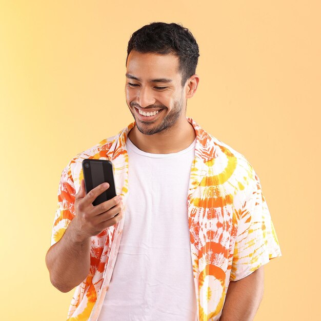 Man with smartphone in hand smile and happy with chat or social media communication isolated on studio background Technology happiness and funny meme phone with internet wifi and mockup