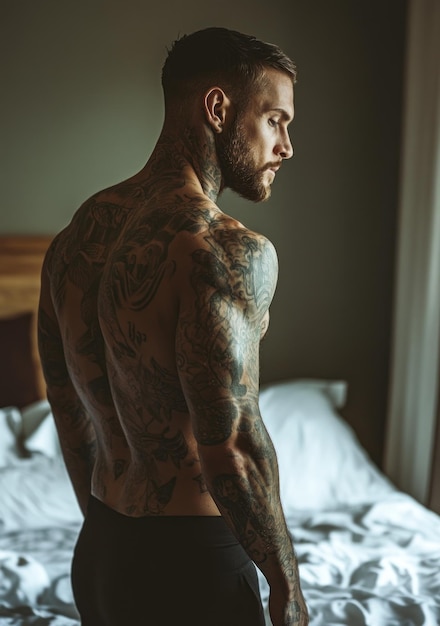 Photo a man with tattoos on his back looks into the camera