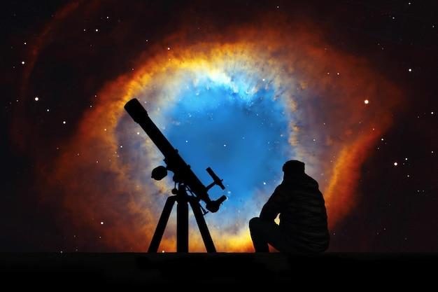 Man with telescope looking at the stars. The Helix Nebula or NGC 7293 in the constellation Aquarius. Elements of this image are furnished by NASA.