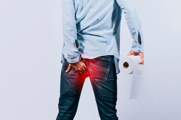 Man with toilet paper in hand touching his buttock Man with diarrhea problem man with hemorrhoid problem on isolated background