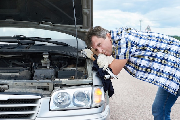 Man with tools near broken car