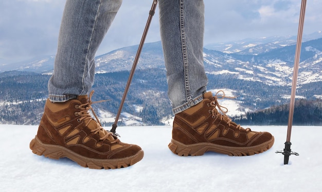 Man with trekking poles in snowy mountains closeup