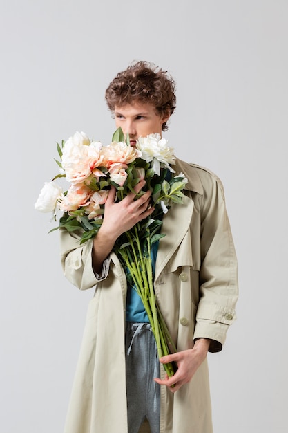 Man with trench coat holding flowers