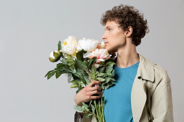 Man with trench coat holding flowers