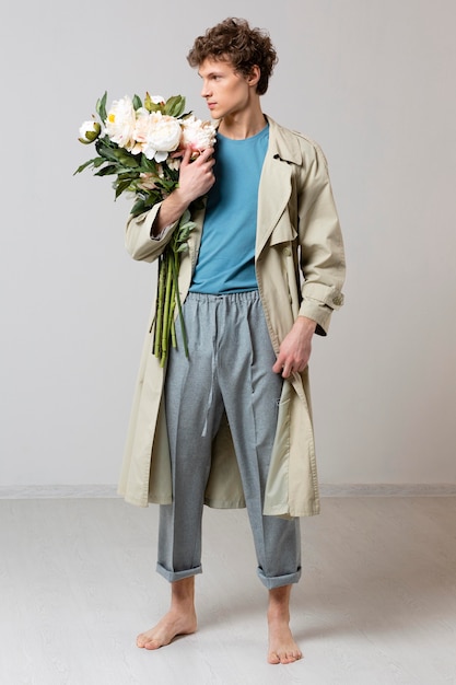 Man with trench coat holding flowers