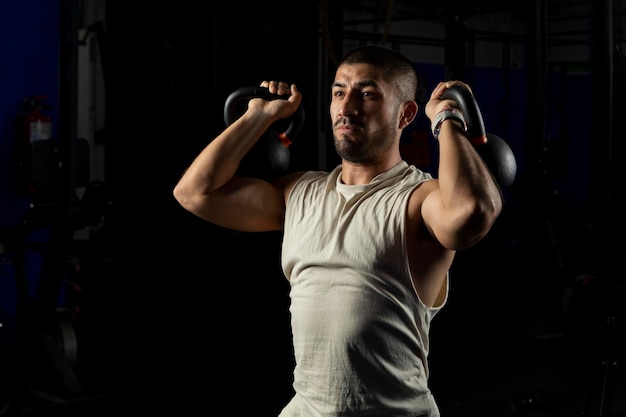 Man with two kettlebells doing arm exercises in the gym