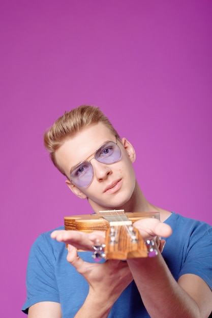 Man with ukulele in hands on purple background