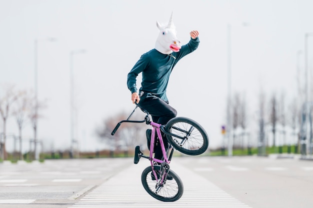 Man with unicorn mask riding a bicycle