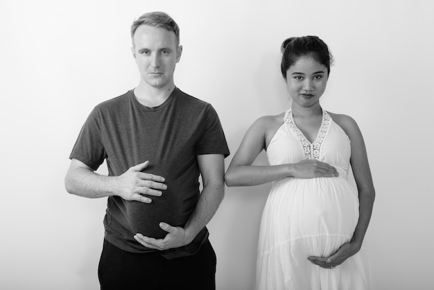 Photo man with watermelon as stomach and pregnant asian woman together as multi ethnic married couple in black and white