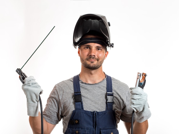 A man with a welding mask on his head, raised up, open face, holding welding wires and an electrode in his hands.