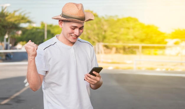 Man with winning gesture using cell phone in the street Happy young man with winning gesture with cellphone on the street Happy Caucasian handsome man using cellphone on the street