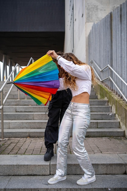 Photo a man and a woman are holding a rainbow colored umbrella