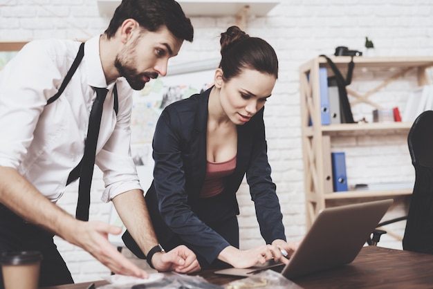 Man and woman are looking at clues on laptop.