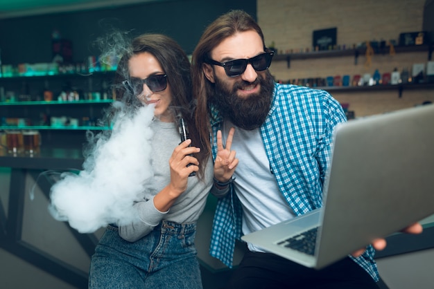 Photo a man and a woman are sitting with an vaporizer and laptop.