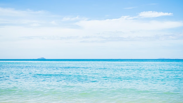 A man and woman are standing on the beach in front of a blue ocean.