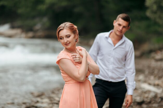 Photo a man and a woman are standing on a rocky shore