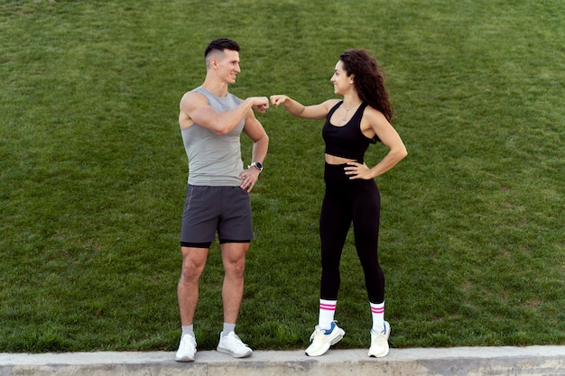 Man and woman bumping fists with each other after morning training and posing