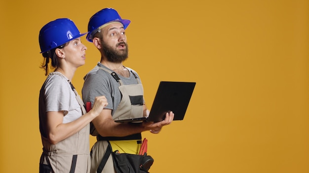 Man and woman contractors using laptop to do rebuilding measurement, working on brainstorming ideas and calculation to do deconstruction and refurbishment. Planning construction site.