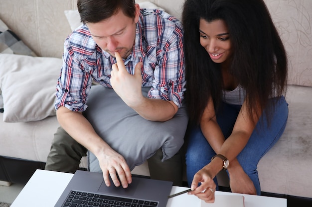 Man and woman on couch and looking at laptop